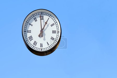 Foto de Calle reloj redondo con números romanos en un cielo azul claro - Imagen libre de derechos