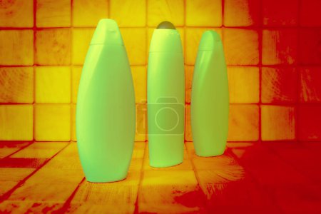 Foto de Botellas de plástico verde brillante para detergentes naranja madera fondo cuadrados - Imagen libre de derechos