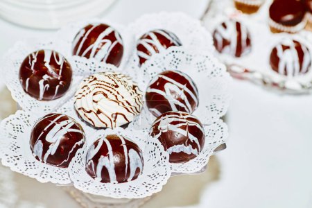 Téléchargez les photos : Ensemble de bonbons au chocolat ronds, décorés de lignes de crème blanche - en image libre de droit