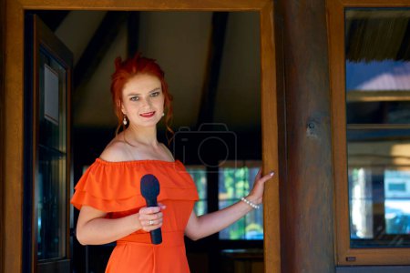 Gastgeber der Hochzeitszeremonie. Junge Frau im roten Kleid mit Mikrofon                               
