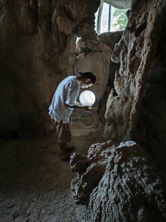 Téléchargez les photos : Modèle masculin tenant une boule de cristal brillant dans la main à l'intérieur de la grotte sombre. - en image libre de droit