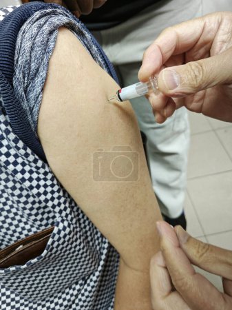 Bild von jemandem, der sich am Oberarm impfen lässt.