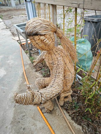 figure of a man sitting on the bench made of dried straw.