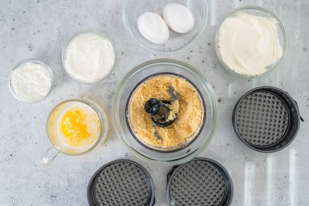 Photo for Crushed crackers, melted butter, cream cheese, eggs, and some other ingredients for the cheesecake recipe close-up, flat lay - Royalty Free Image