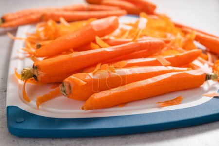 Téléchargez les photos : Peeled carrots close-up on a cutting board on a light grey stone background with copy space - en image libre de droit