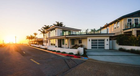 Beautiful houses with ocean views, with nicely landscaped front the yard in a small beach town somewhere in California at sunset