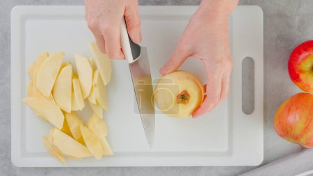 Téléchargez les photos : Woman hands slicing apple on a white cutting board on the kitchen table, flat lay - en image libre de droit