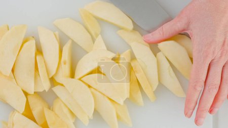 Téléchargez les photos : Woman hands slicing apple on a white cutting board on the kitchen table, flat lay - en image libre de droit