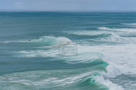 Ein einsamer Surfer reitet auf einer immensen Welle und präsentiert die beeindruckende Brandung, für die Nazare berühmt ist. Portugal, Silberküste