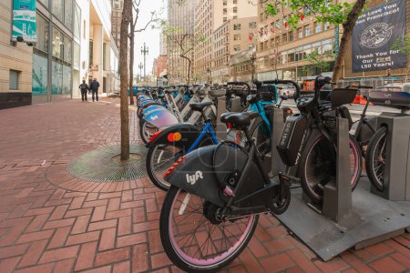 Photo for San Francisco, California, April 8, 2024. Docked bikes await riders on a San Francisco sidewalk with urban life in the background. - Royalty Free Image