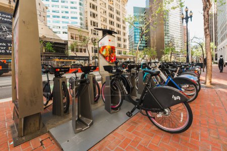 Photo for San Francisco, California, April 8, 2024. Docked bikes await riders on a San Francisco sidewalk with urban life in the background. - Royalty Free Image