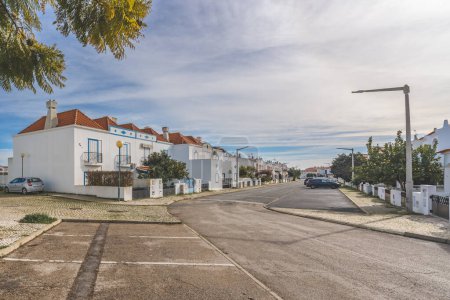 Foto de Manta Rota, Portugal, 10 de enero de 2024. Una calle residencial en Manta Rota, Portugal, con casas blancas con acentos amarillos, caminos empedrados y exuberantes árboles verdes. - Imagen libre de derechos