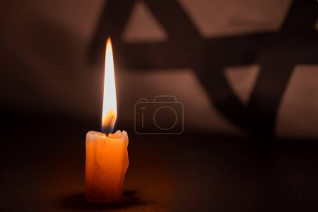 Photo for Holocaust Remembrance Day. Yom HaShoah. Bright Burning Candle and the official flag of Israel on a dark grey background. Memorial Day for Jewish people. - Royalty Free Image