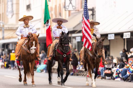 Photo for Brownsville, Texas, USA - February 26, 2022: Charro Days Grand International Parade, men in charro outfits carry the mexican and american national flags - Royalty Free Image