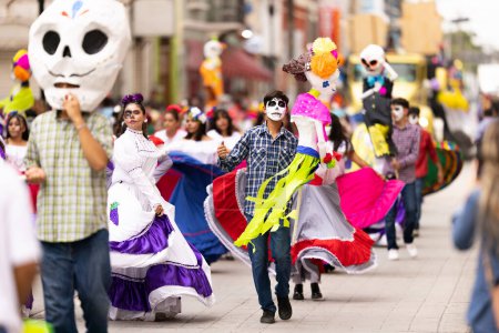 Foto de Matamoros, Tamaulipas, México - 1 de noviembre de 2022: Desfile Dia de los Muertos, mujeres jóvenes y hombres vestidos con ropa tradicional bailando con títeres durante el desfile - Imagen libre de derechos