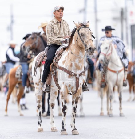 Téléchargez les photos : Valle Hermoso, Tamaulipas, Mexique - 18 mars 2023 : Défilé d'anniversaire de la ville, Grand groupe de cow-boys chevauchant leurs chevaux à la fin du défilé sur la deuxième rue - en image libre de droit