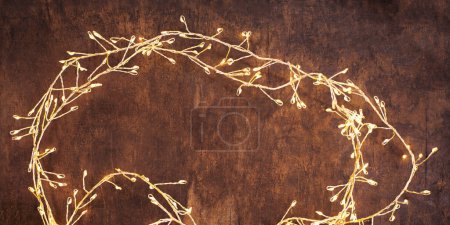 Téléchargez les photos : Christmas lights on a brown wood background. Golden Christmas garland top view, copyspace - en image libre de droit