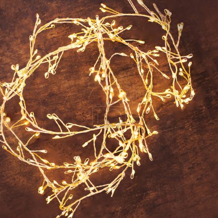 Photo for Christmas lights on a dark wooden background. Golden Xmas decorations sparkling garland top view, - Royalty Free Image