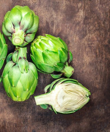 Photo for Artichoke flower buds. Fresh and raw artichoke on the wooden tabl - Royalty Free Image