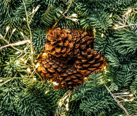 Foto de Ramas de árboles de Navidad con luces doradas guirnalda y cono como una vista superior de fondo. Patrón de Navidad, concepto de año nuevo de la naturaleza - Imagen libre de derechos