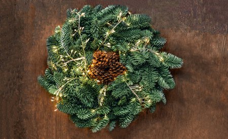 Foto de Christmas wreath with golden lights on dark rustic background  top view, copyspace. Xmas garland, New Year concept - Imagen libre de derechos
