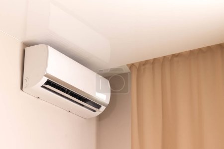Photo for White air conditioner under stretch ceiling in modern room with beige curtains - Royalty Free Image