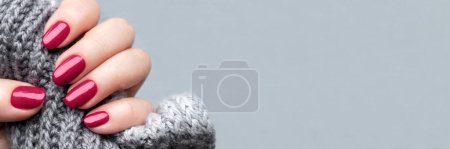 Téléchargez les photos : Main féminine avec foulard tricoté et belle manucure - viva magenta, ongles pailletés bordeaux avec espace de copie. Large bannière panoramique, en-tête - en image libre de droit