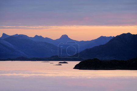 Photo for Midsummer sunlight on the sky and mountains silhouettes in the fjord Vestfjorden near the Lofoten islands and town Svolvaer, Norway - Royalty Free Image