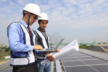 Photo for Solar engineer and technician discussing about blue print drawing on roof of factory, Solar green renewal energy ,Engineer and businessman working onsite at solar roof, Progressive with solar project - Royalty Free Image