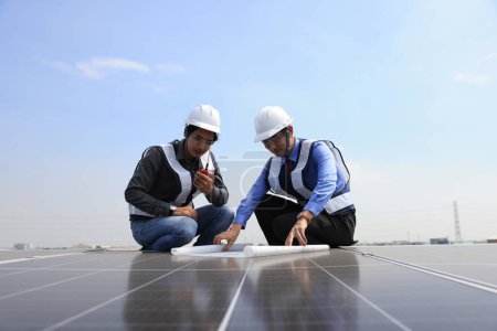Photo for Solar engineer and technician discussing about blue print drawing on roof of factory, Solar green renewal energy ,Engineer and businessman working onsite at solar roof, Progressive with solar project - Royalty Free Image