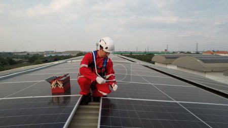 Téléchargez les photos : Installation de toit solaire, Ingénieur avec EPI de sécurité et Harnais installer des cellules solaires sur le toit de l'usine, énergie renouvelable verte - en image libre de droit