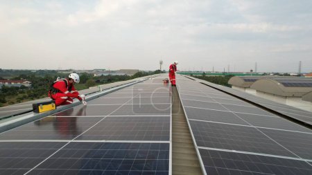 Photo for Solar roof installation, Engineer with safety PPE and Harness install solar cells on the roof of the factory , green renewable energy - Royalty Free Image