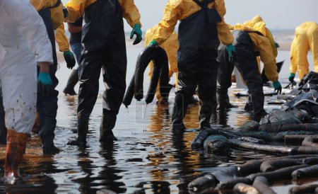 Foto de Equipo profesional y voluntario vistiendo PPE limpiar sucio de derrame de petróleo en la playa, mancha de aceite lavada en una playa de arena - Imagen libre de derechos