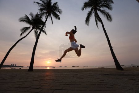 Téléchargez les photos : Femme incroyable saine et joyeuse sauter parmi le cocotier sur la plage - en image libre de droit