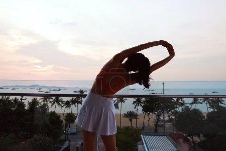 Foto de Mujer sana estiramiento y ejercicio en el balcón del hotel en frente de Pattaya Beach - Imagen libre de derechos