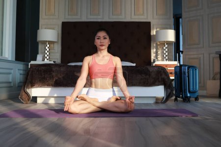 Foto de Mujer joven haciendo yoga en casa en la habitación, concepto de estilo de vida saludable. - Imagen libre de derechos