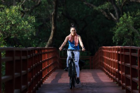Téléchargez les photos : Mode de vie à la retraite, femme en bonne santé faire de l'exercice à vélo dans le jardin - en image libre de droit