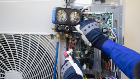Téléchargez les photos : Close up Le technicien du climatiseur vérifie manuellement le liquide réfrigérant et l'unité de condensation d'entretien, service de soins à domicile - en image libre de droit