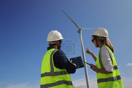 Ein paar Elektrotechniker arbeiten zusammen an einem Windkraftpark.