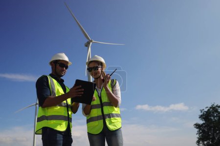 Ein paar Elektrotechniker arbeiten zusammen an einem Windkraftpark.