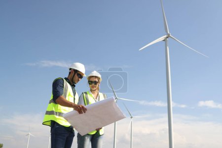 A couple of  Electric engineers working together at a wind turbine farm.