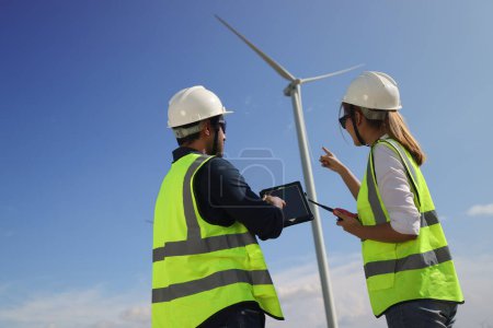 Photo for A couple of  Electric engineers working together at a wind turbine farm. - Royalty Free Image