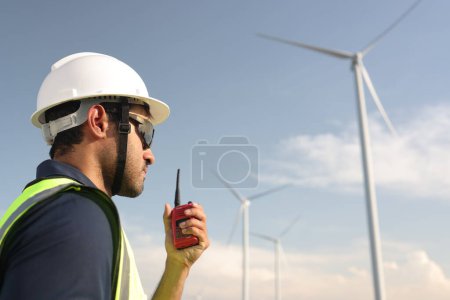 Photo for International Women's Day, you Asian woman with a green safety vest using a talkie at a windmill farm - Royalty Free Image