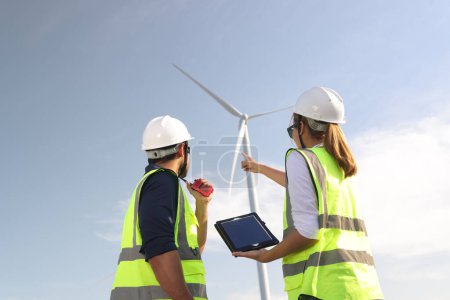 Photo for A couple of  Electric engineers working together at a wind turbine farm. - Royalty Free Image