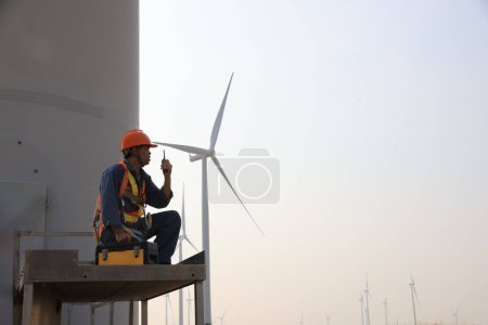 Téléchargez les photos : Technicien spécialisé en éoliennes travaillant à la base de l'éolienne. Technicien d'entretien d'éoliennes portant un uniforme de sécurité et un harnais de sécurité travaillant dans un parc éolien - en image libre de droit