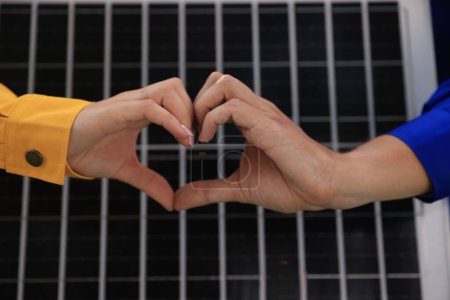 Téléchargez les photos : A couple of engineering workers make heart shapes with solar panel prototypes for renewable energy outdoors - en image libre de droit