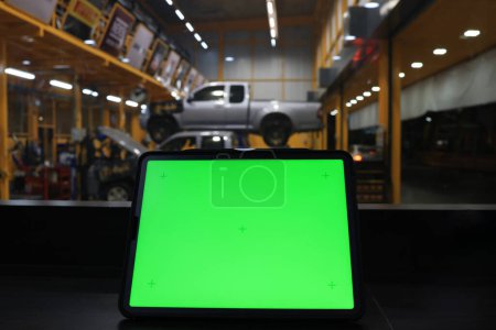 Foto de Pantalla verde en el ordenador portátil contra el garaje del coche, espacio de trabajo de pantalla verde con servicio de mantenimiento del coche en segundo plano - Imagen libre de derechos