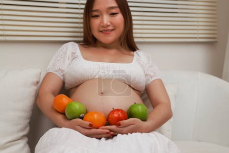 Téléchargez les photos : Femme enceinte préparant des aliments sains avec beaucoup de fruits et légumes à la maison - en image libre de droit