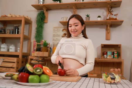 Foto de Mujer embarazada preparando alimentos saludables con muchas frutas y verduras en casa - Imagen libre de derechos