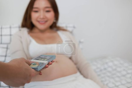 Téléchargez les photos : Une jeune femme reçoit une compensation pour avoir porté un bébé au nom de quelqu'un d'autre. - en image libre de droit